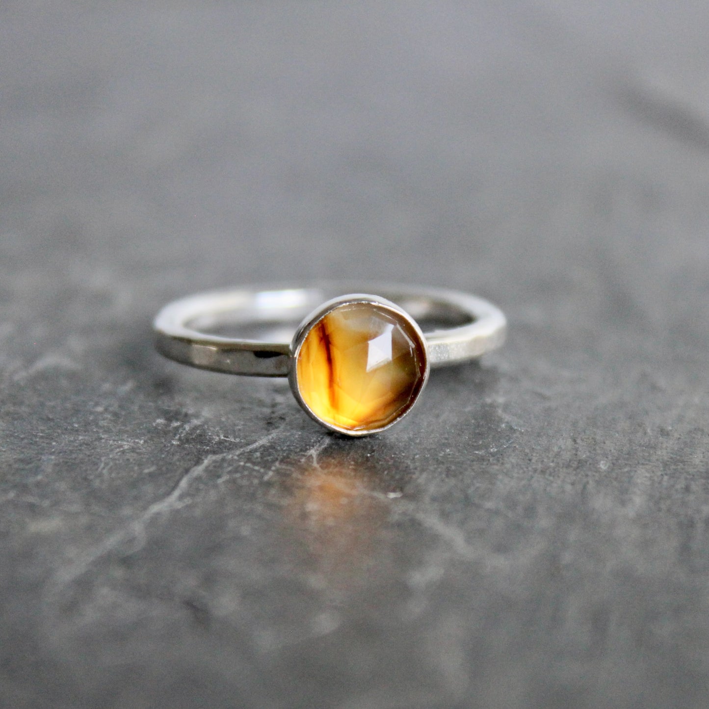 Silver ring with a rose cut montana agate on a gray surface