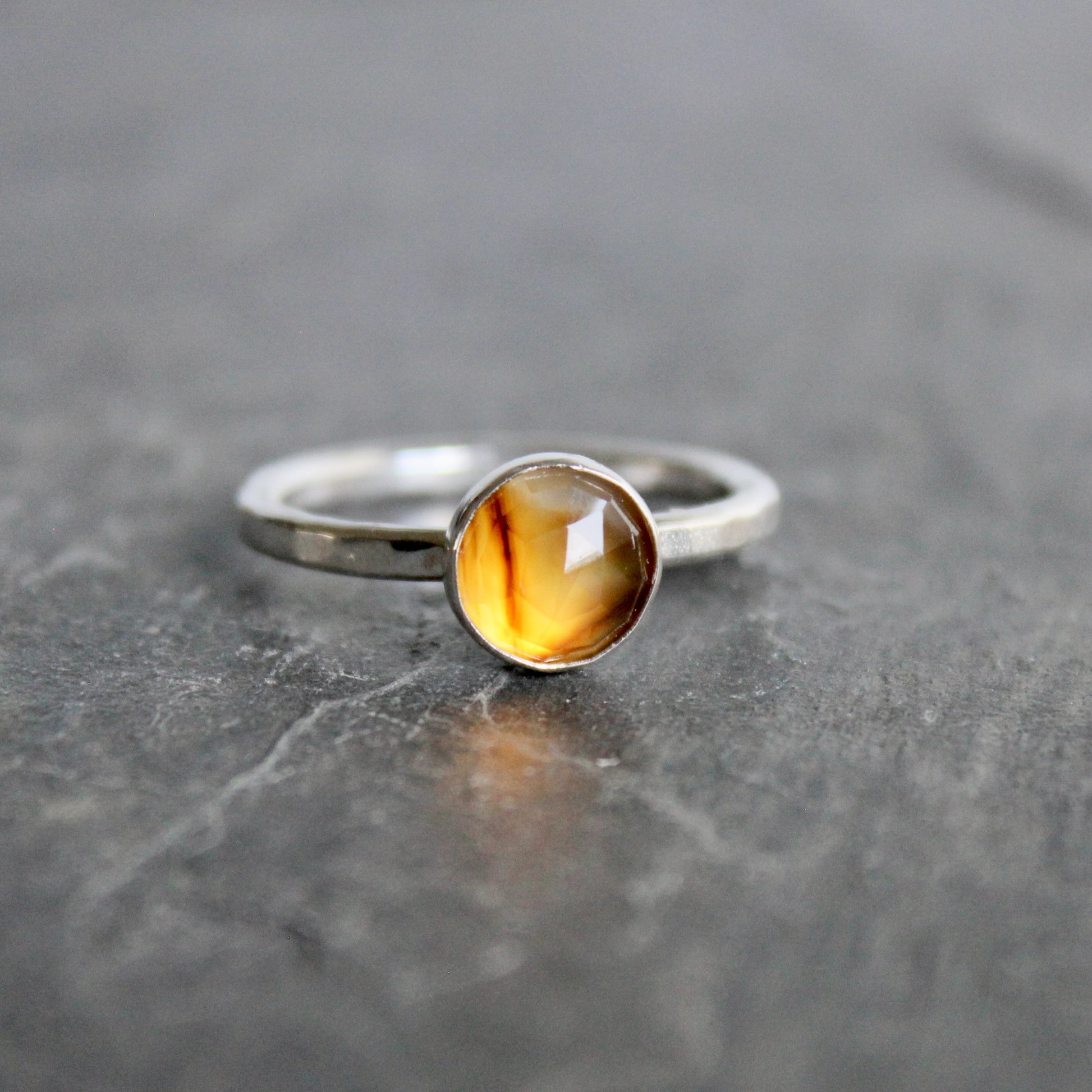 Silver ring with a rose cut montana agate on a gray surface