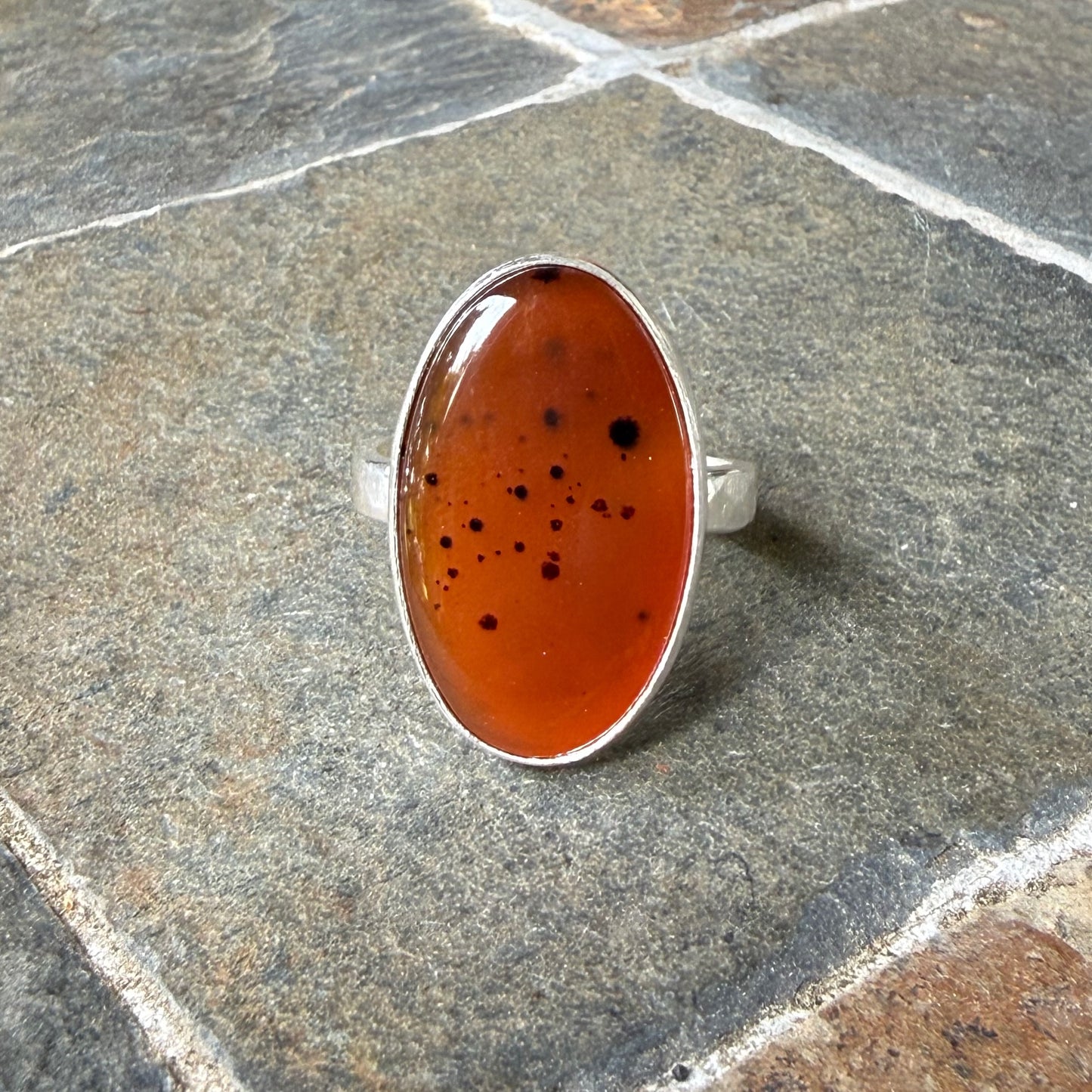 Silver ring with an Orange Montana Agate on a gray surface