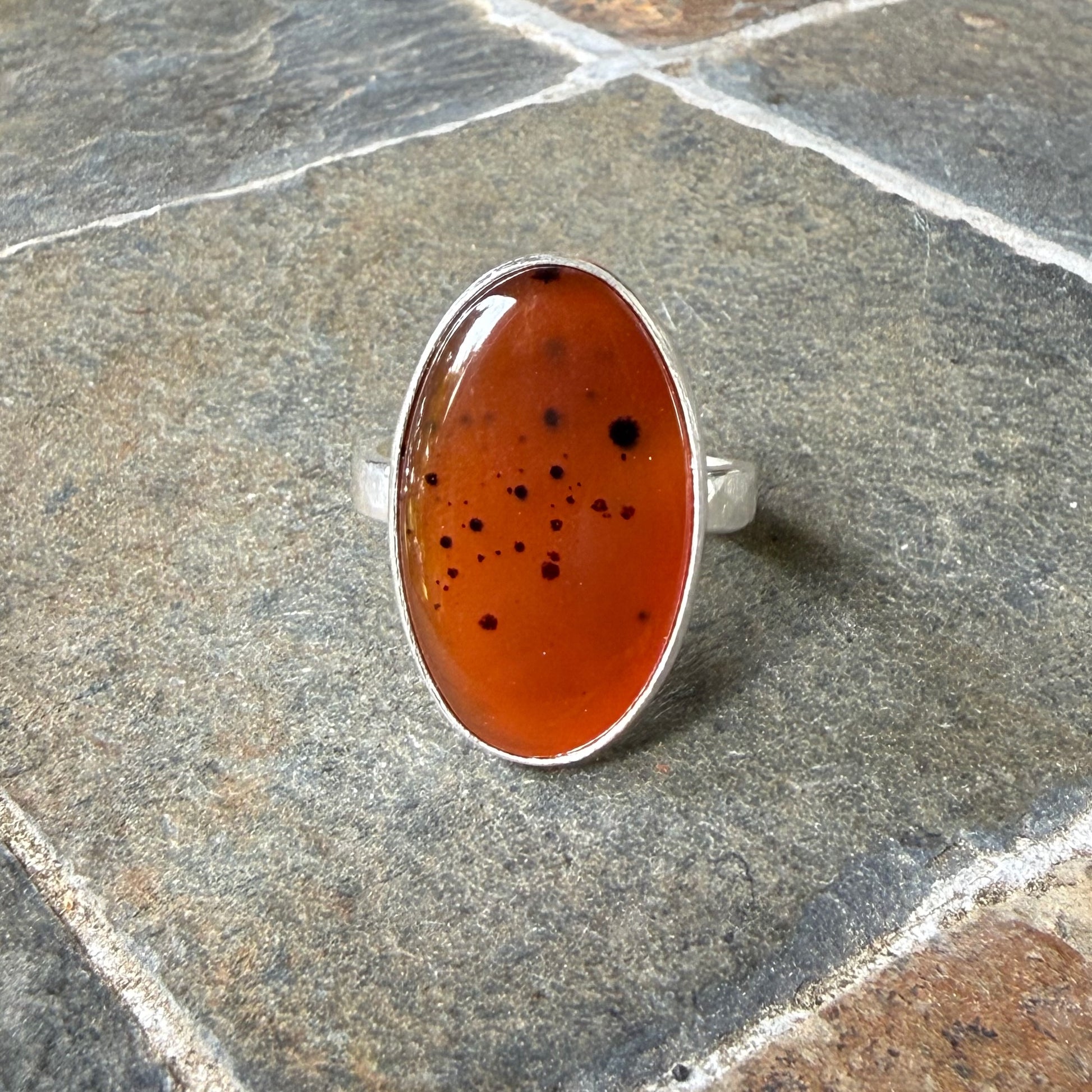 Silver ring with an Orange Montana Agate on a gray surface