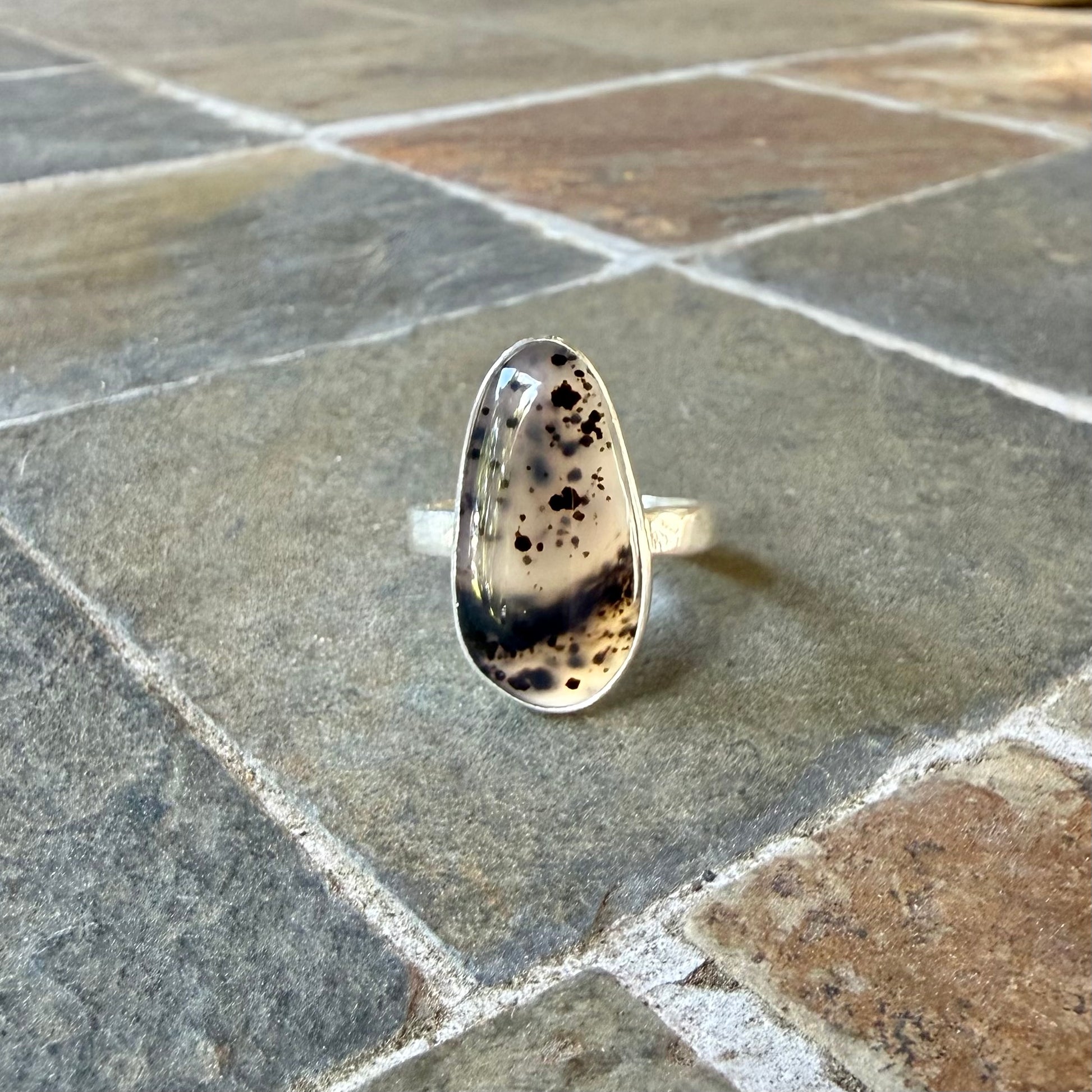 Silver ring with Spotted Montana Agate on a stone surface