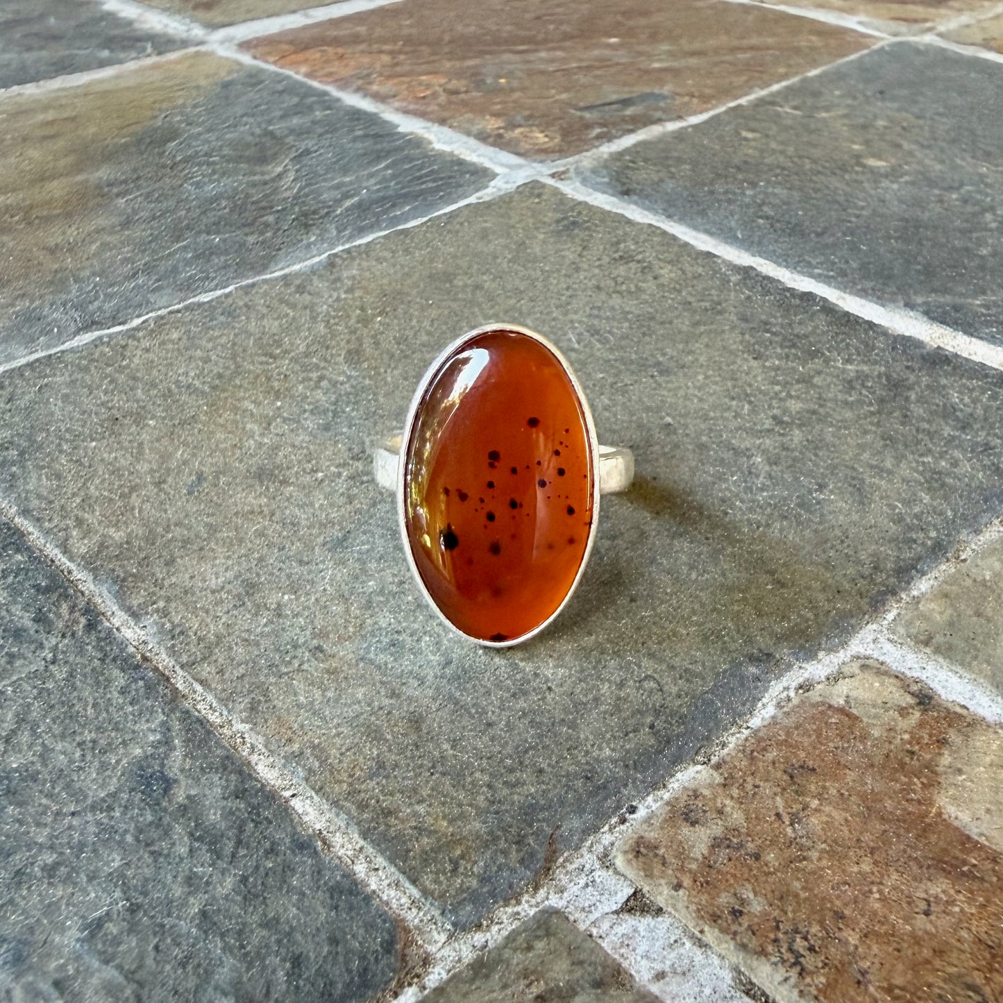 Silver ring with an Orange Montana Agate on a gray surface