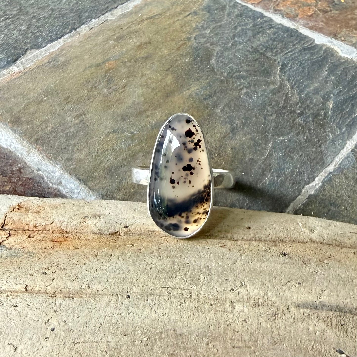 Silver ring with a Spotted Montana Agate design on a stone surface