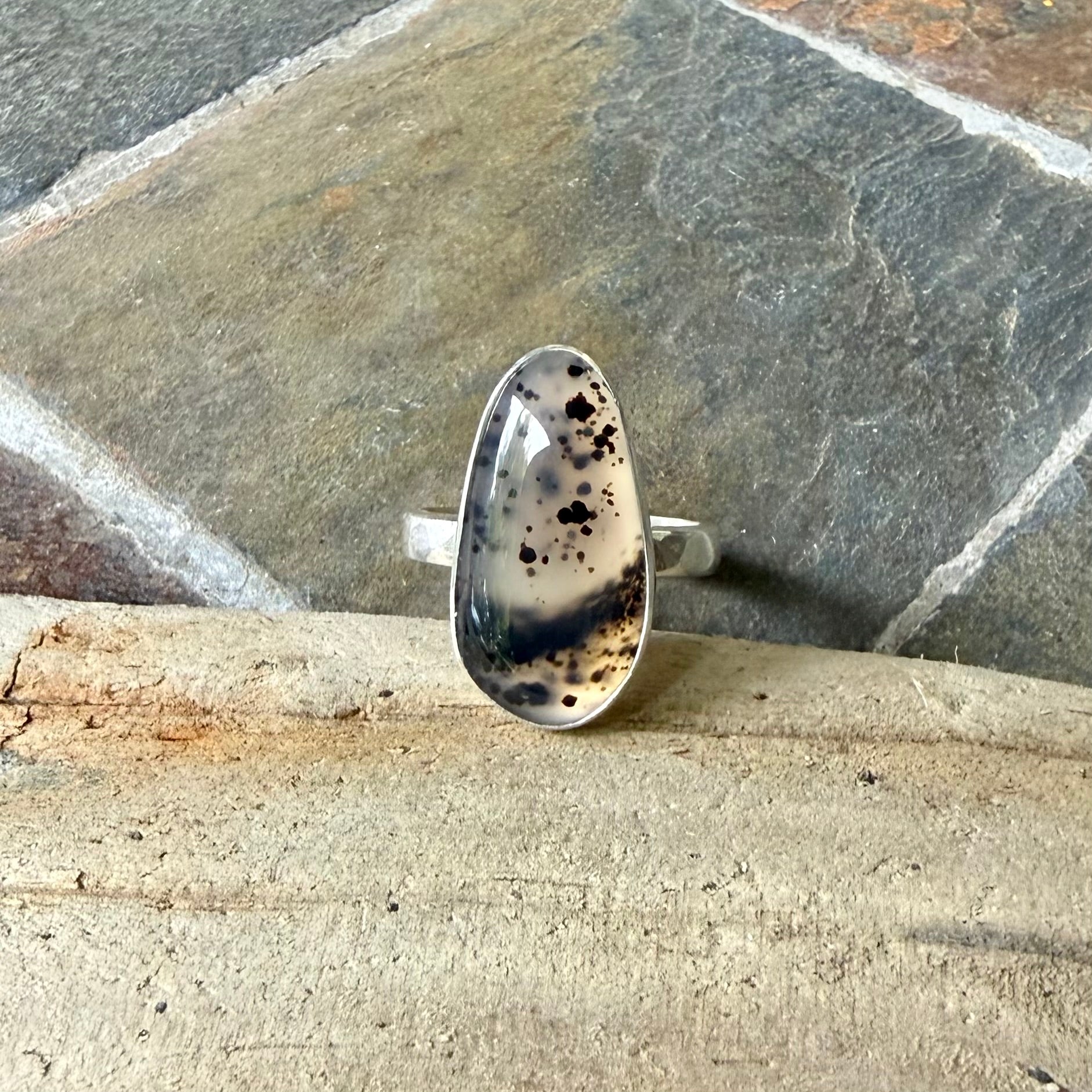 Silver ring with a Spotted Montana Agate design on a stone surface