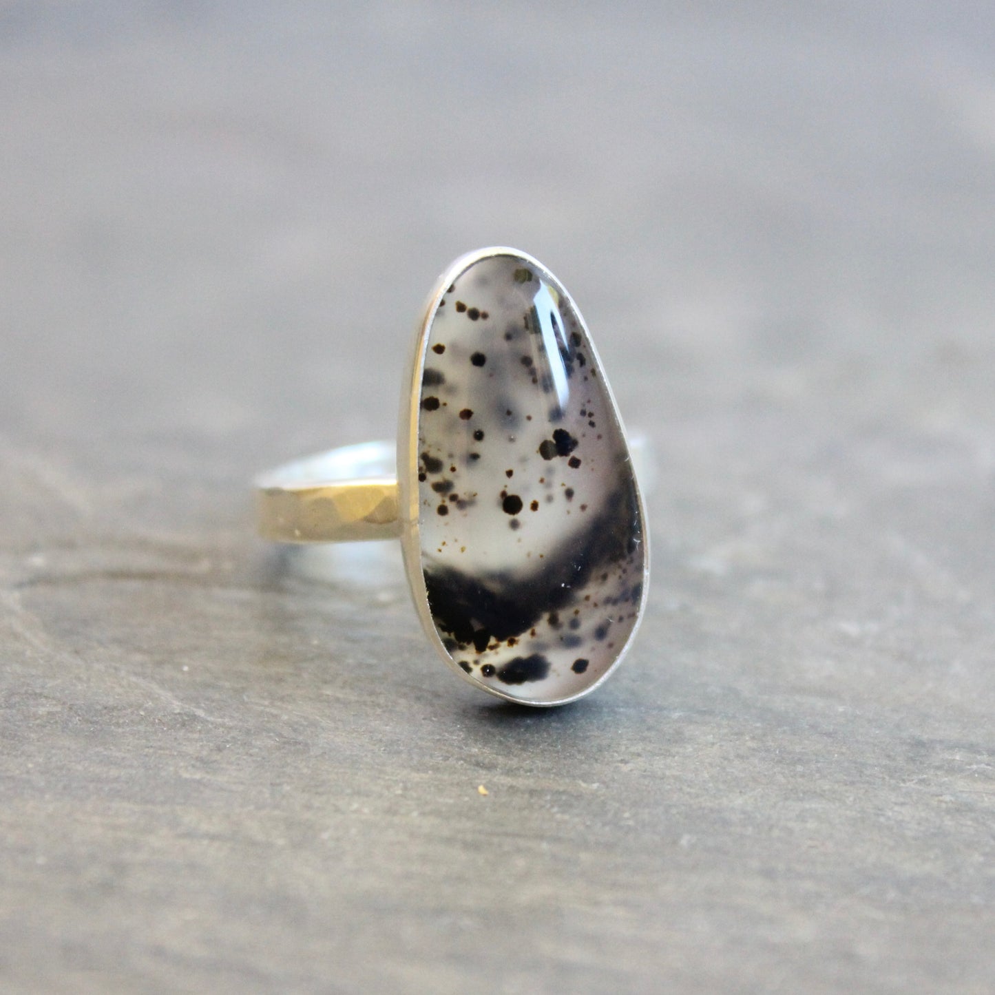 Silver ring with Spotted Montana Agate on a stone surface