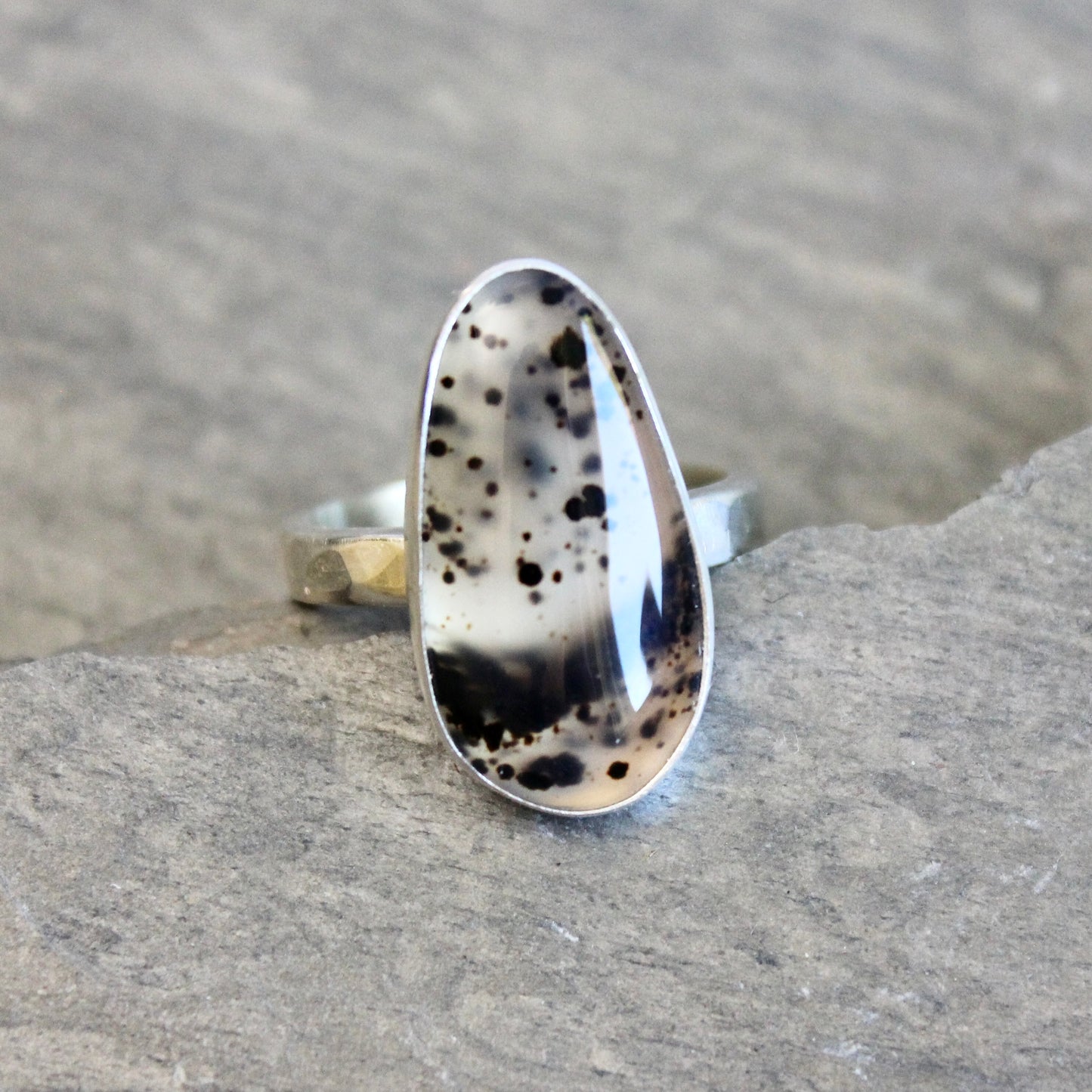 Silver ring with Spotted Montana Agate on a stone surface