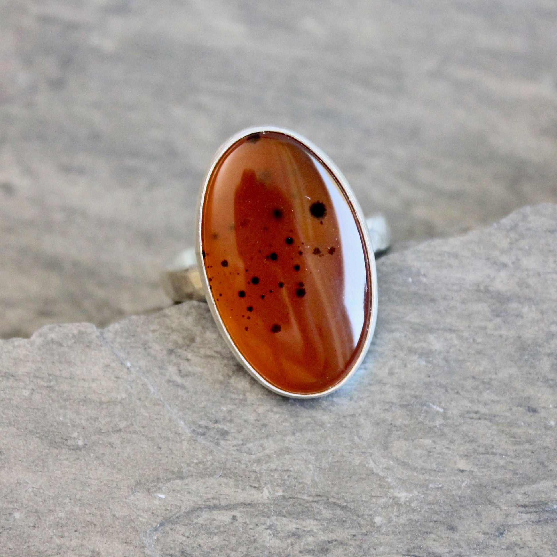 Silver ring with an Orange Montana Agate on a gray surface