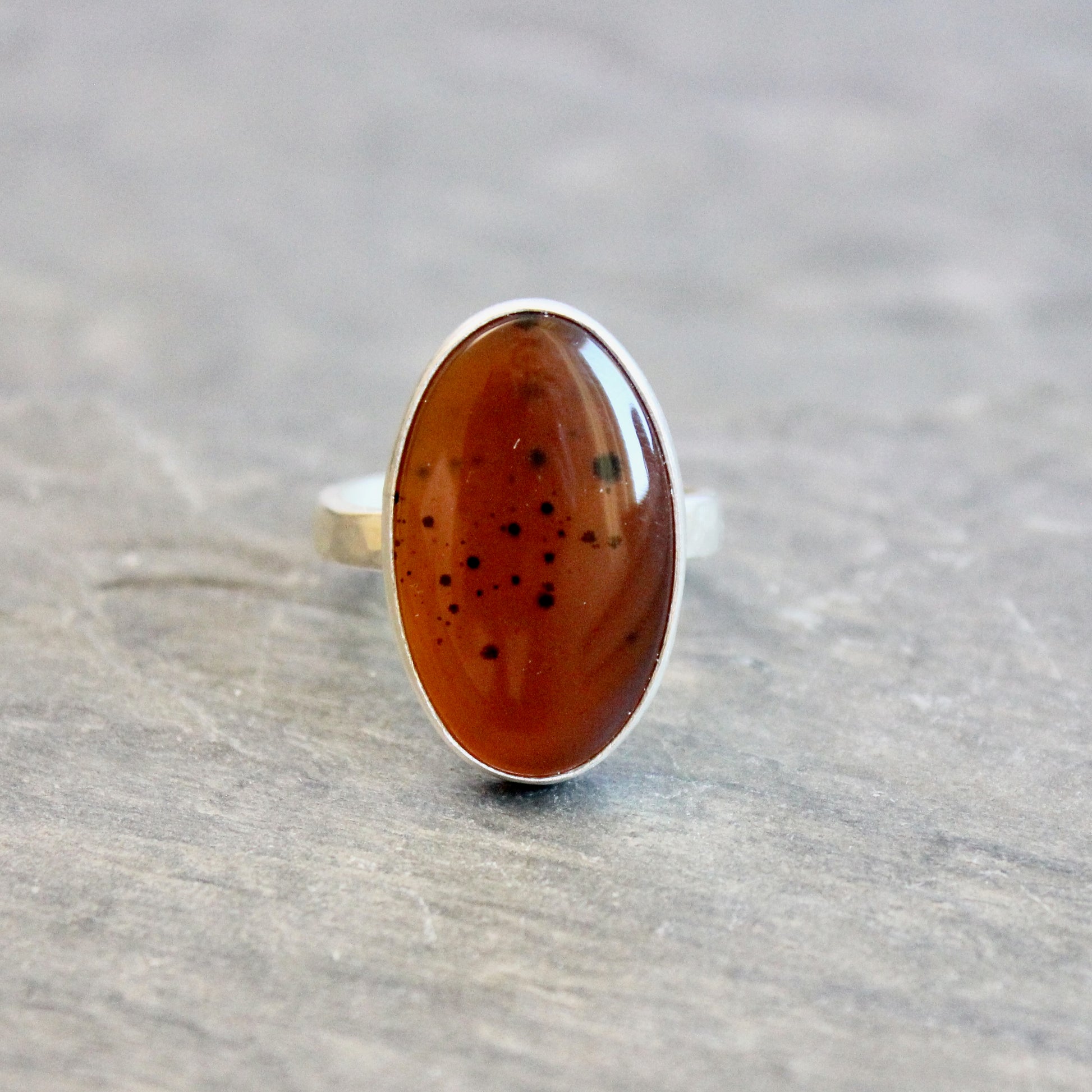 Silver ring with an Orange Montana Agate on a gray surface