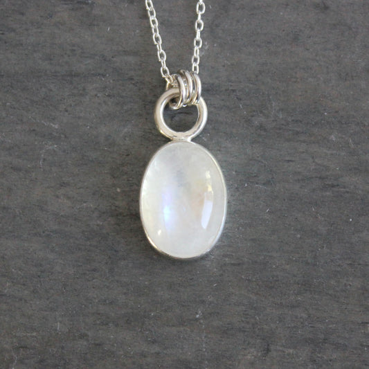 Silver necklace with a moonstone pendant on a dark gray background