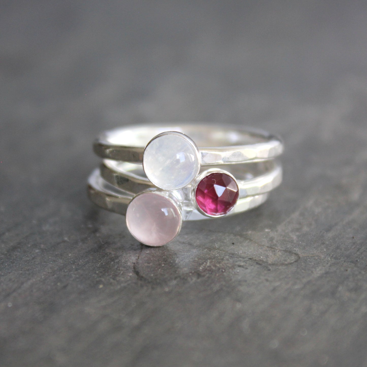 Three silver rings with gemstones on a dark surface