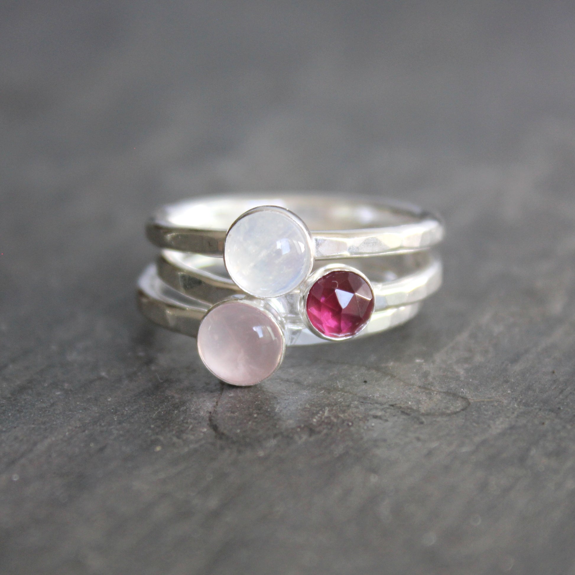 Three silver rings with gemstones on a dark surface