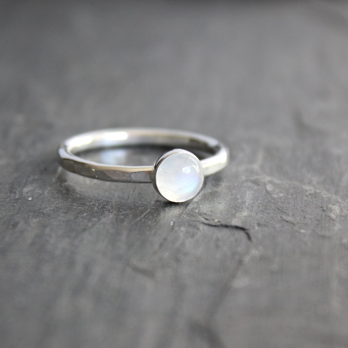 Silver ring with a moonstone on a dark gray surface