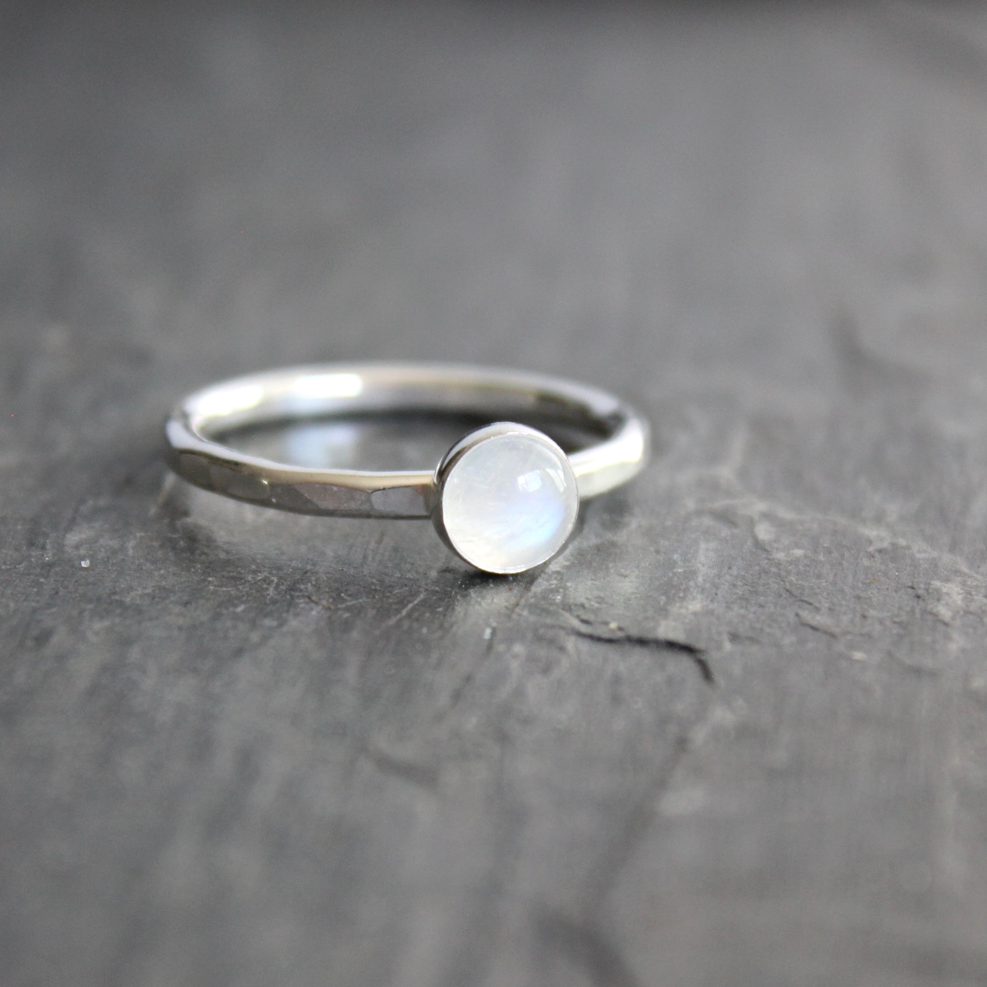 Silver ring with a moonstone on a dark gray surface