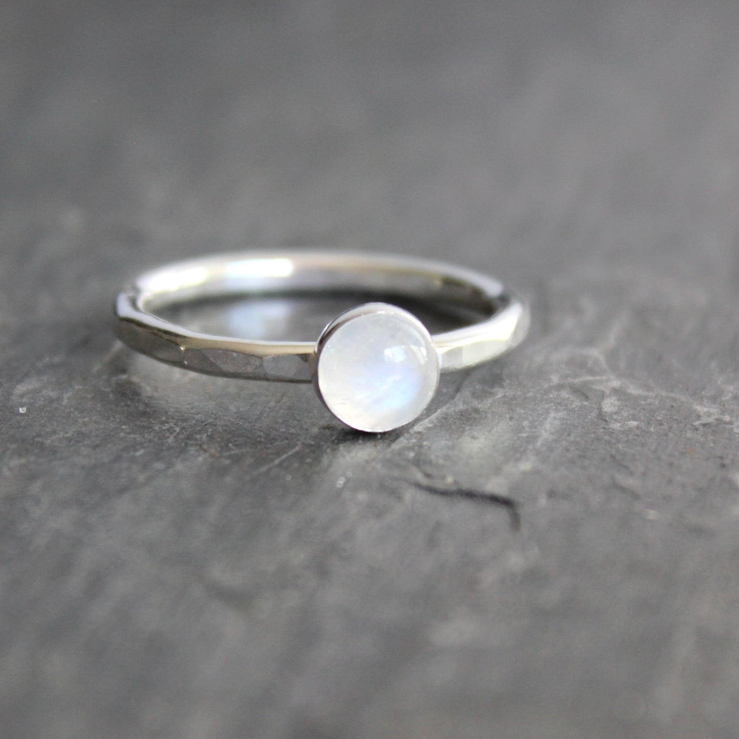 Silver ring with a round moonstone on a dark gray background