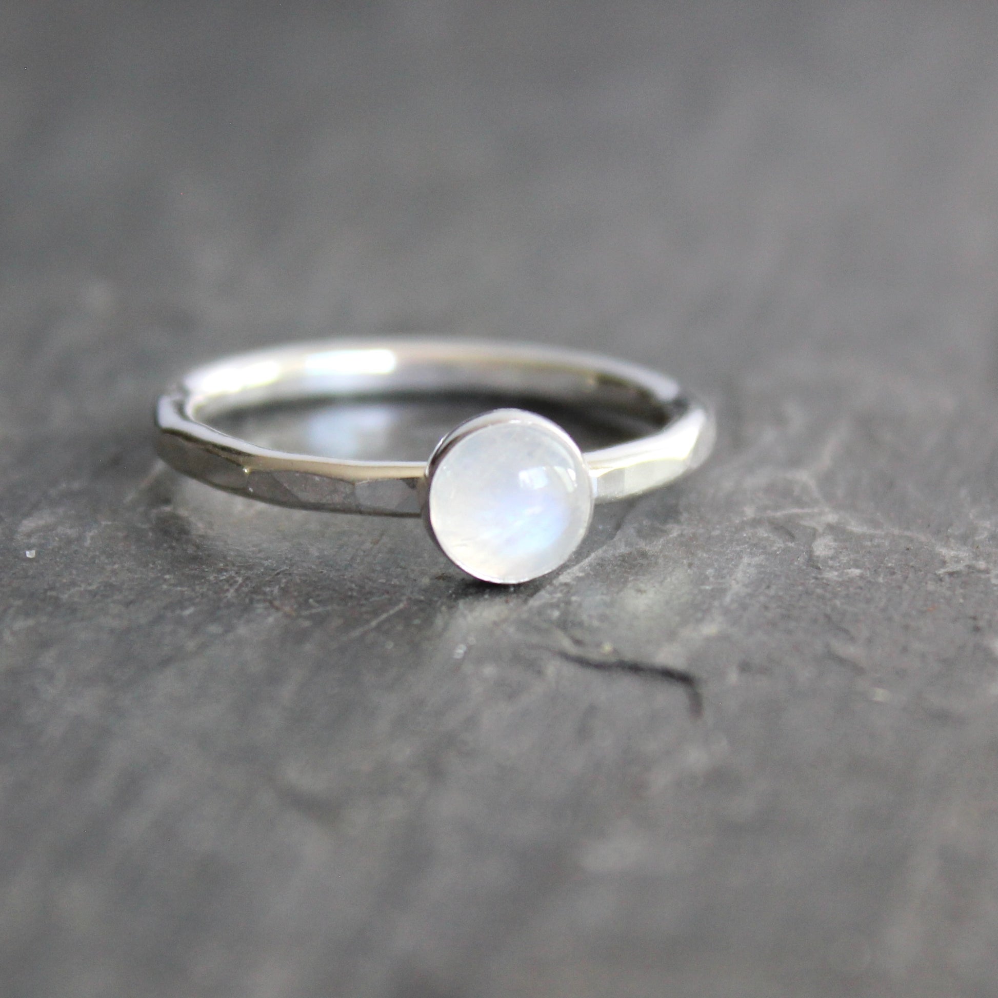 Silver ring with a round moonstone on a dark gray background