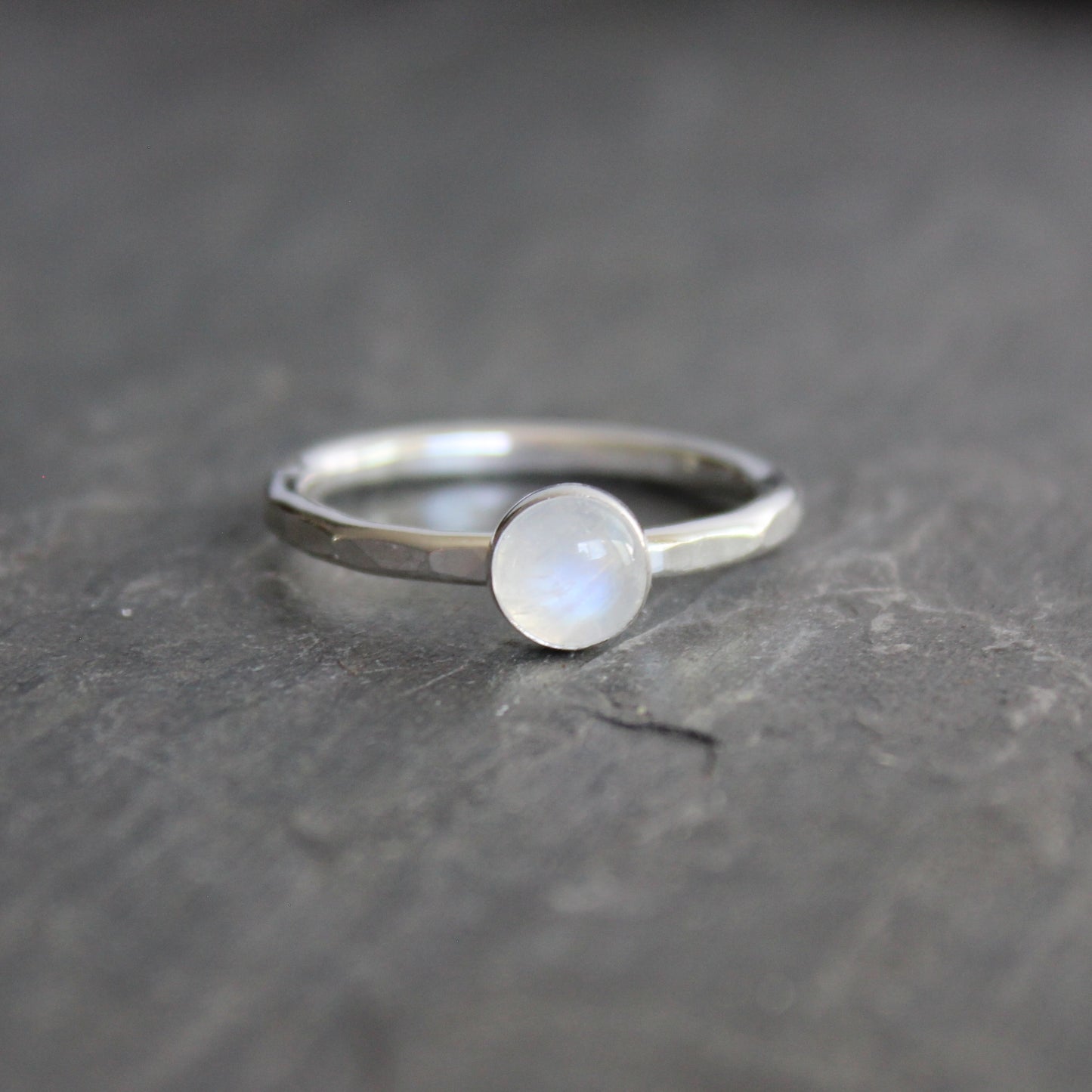 Silver ring with a moonstone on a dark gray surface