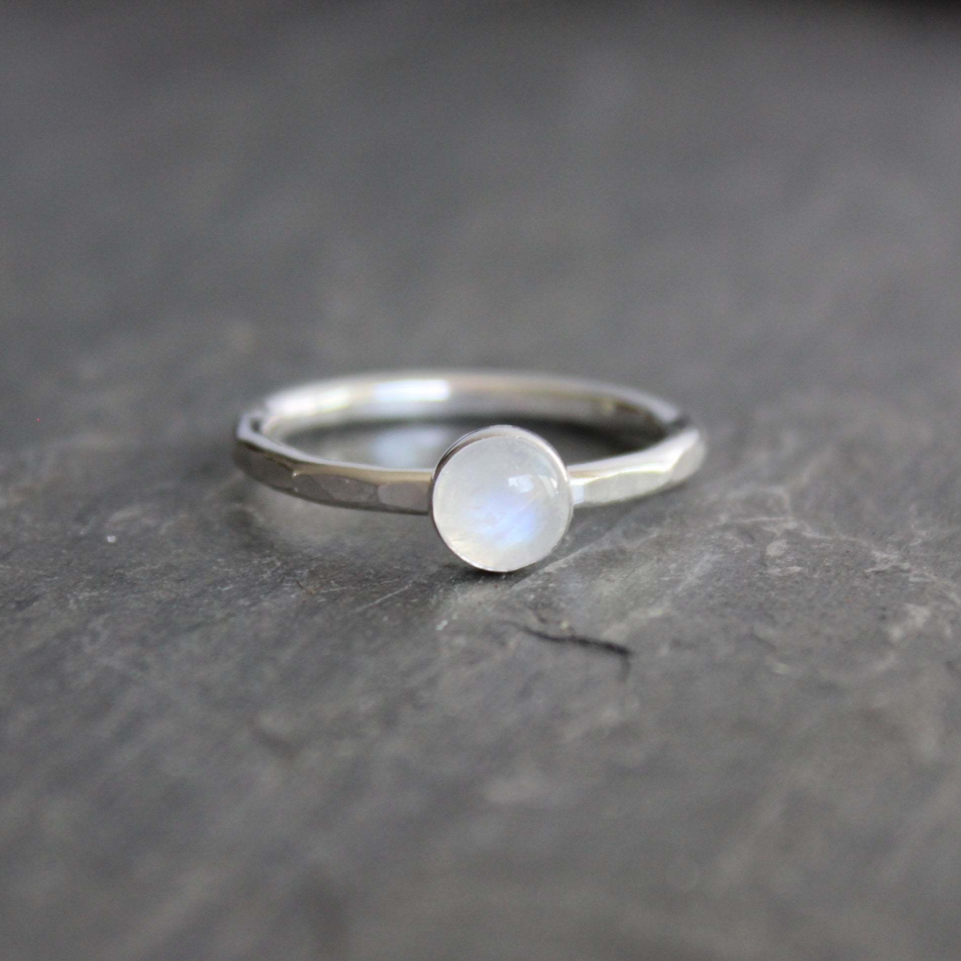 Silver ring with a moonstone on a dark gray surface