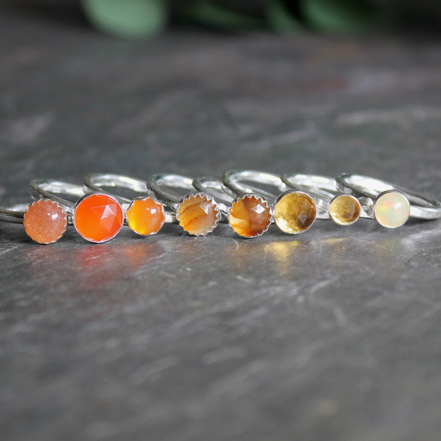 Set of silver rings with colorful gemstones on a dark surface