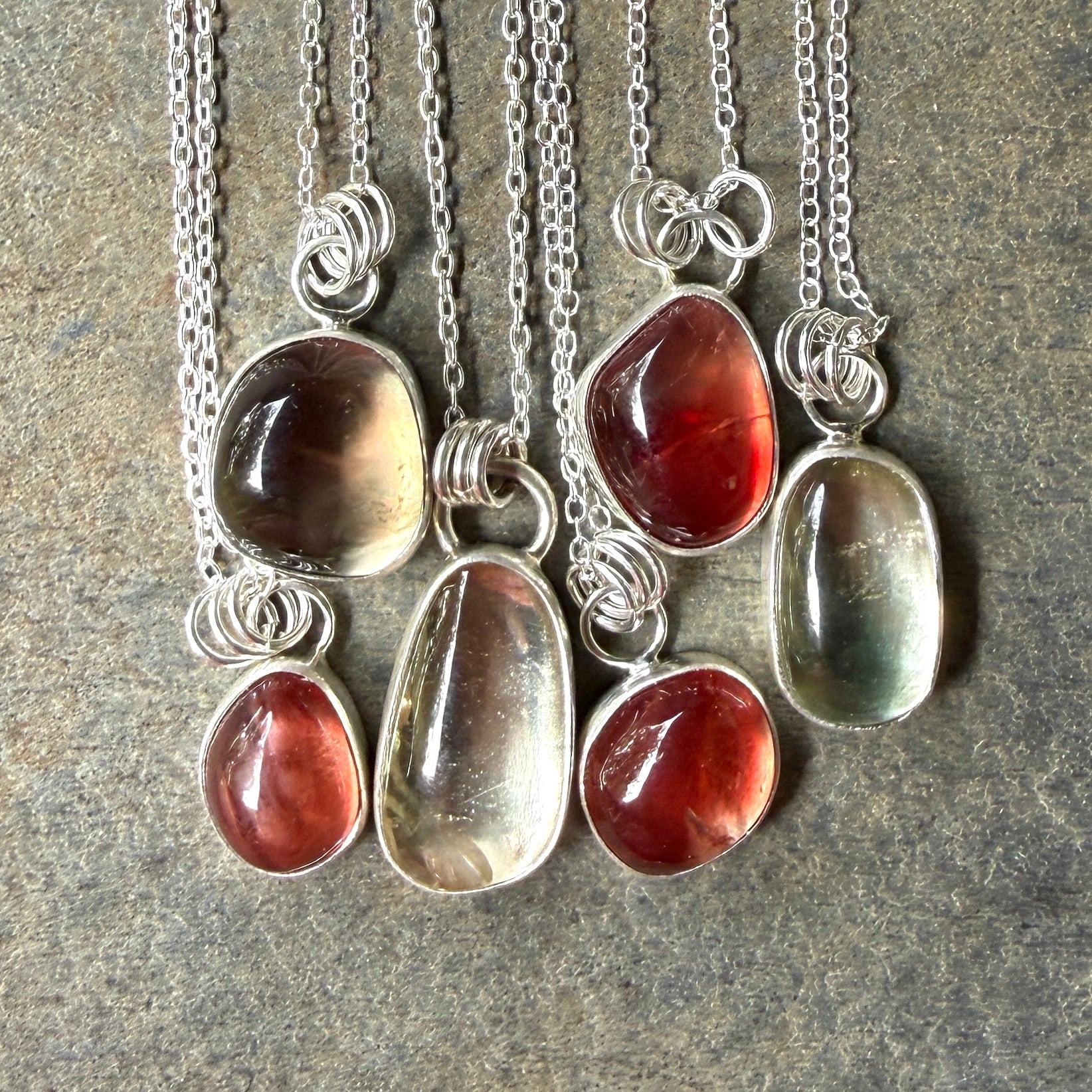 Set of six silver oregon sunstone necklaces on a textured surface