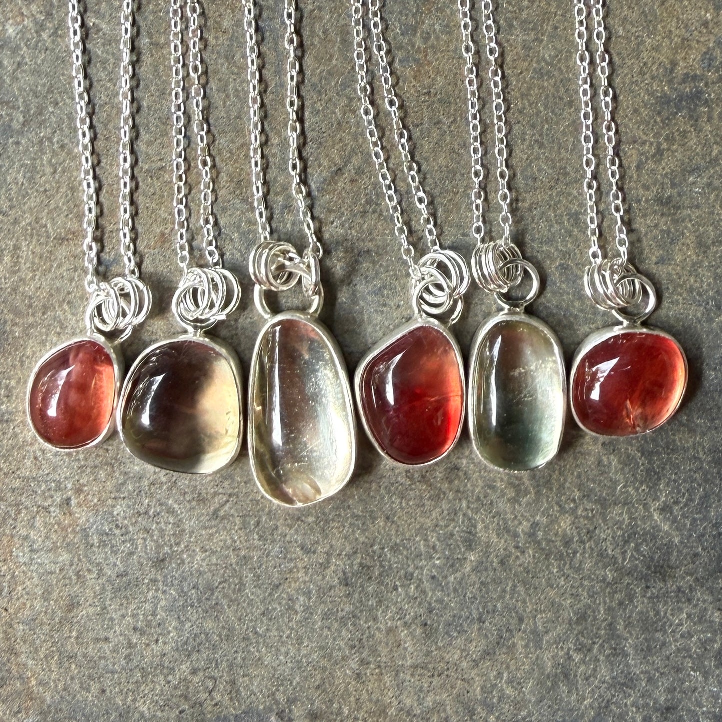 Necklaces with oregon sunstone pendants on a stone surface
