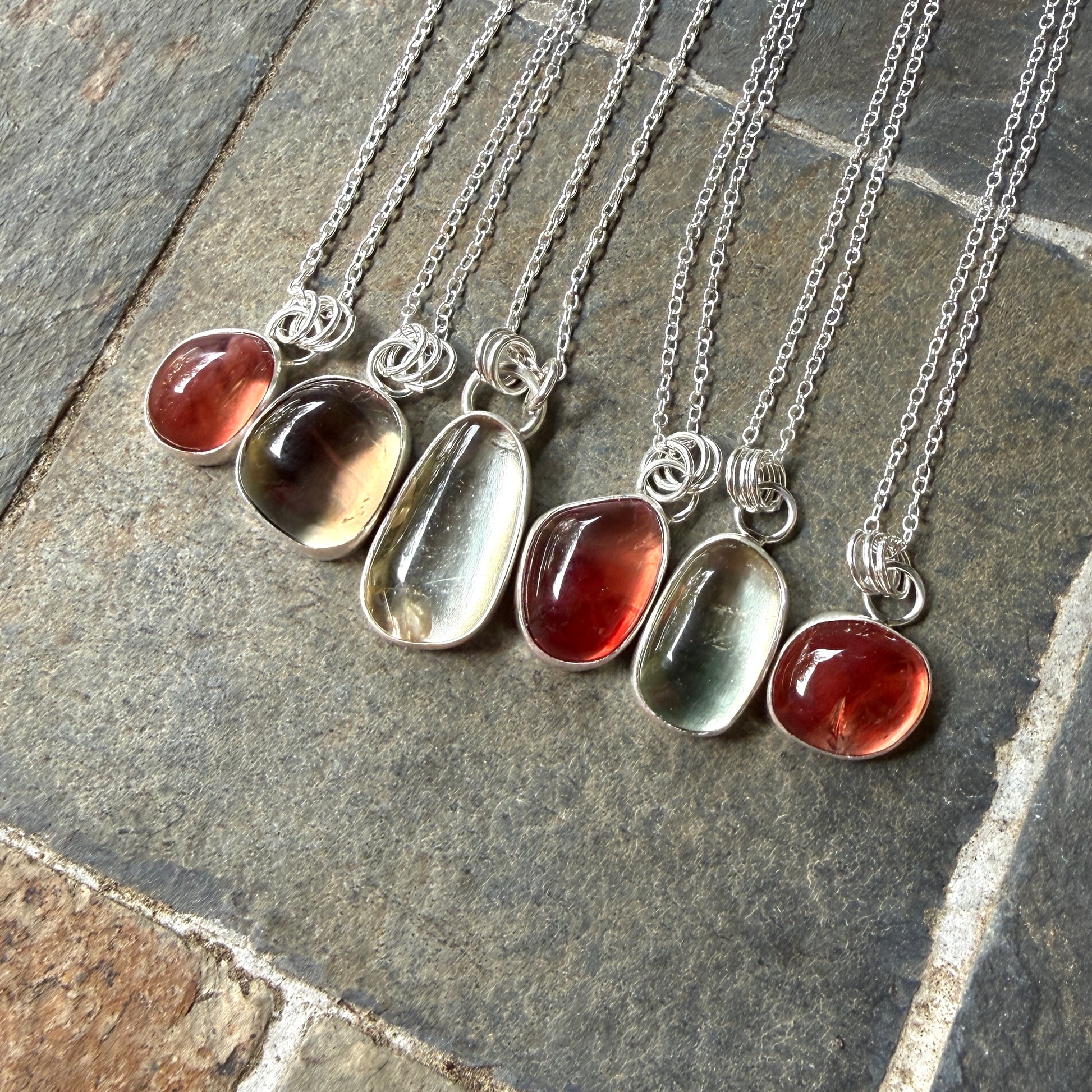 set of six oregon sunstone pendants on a stone surface
