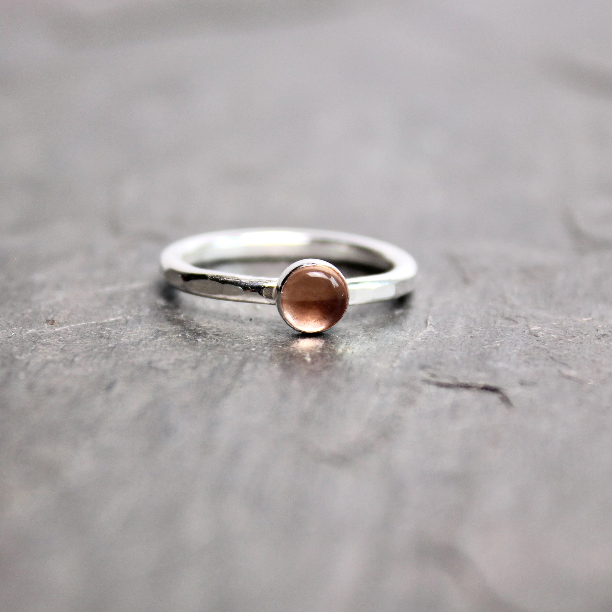 Silver ring with a round oregon sunstone on a gray surface