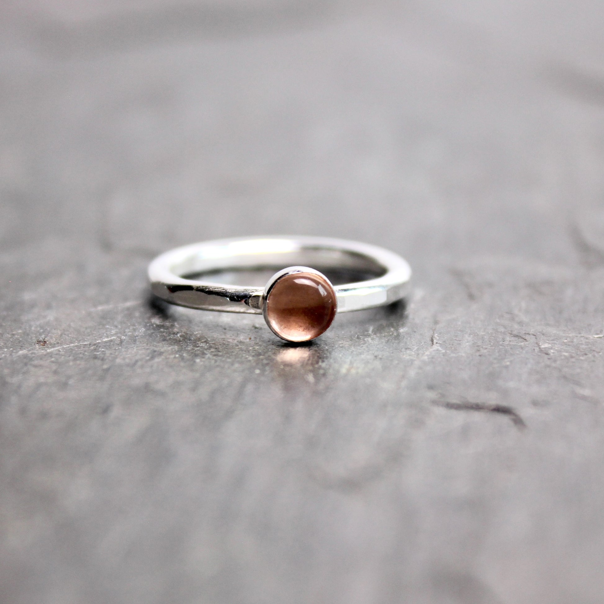 Silver ring with a round oregon sunstone on a gray surface