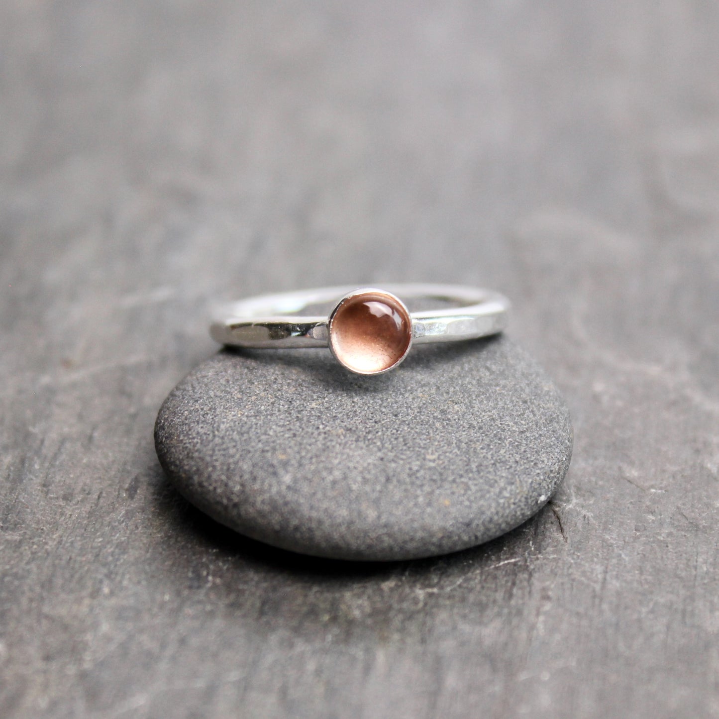Silver ring with a round oregon sunstone on a gray surface