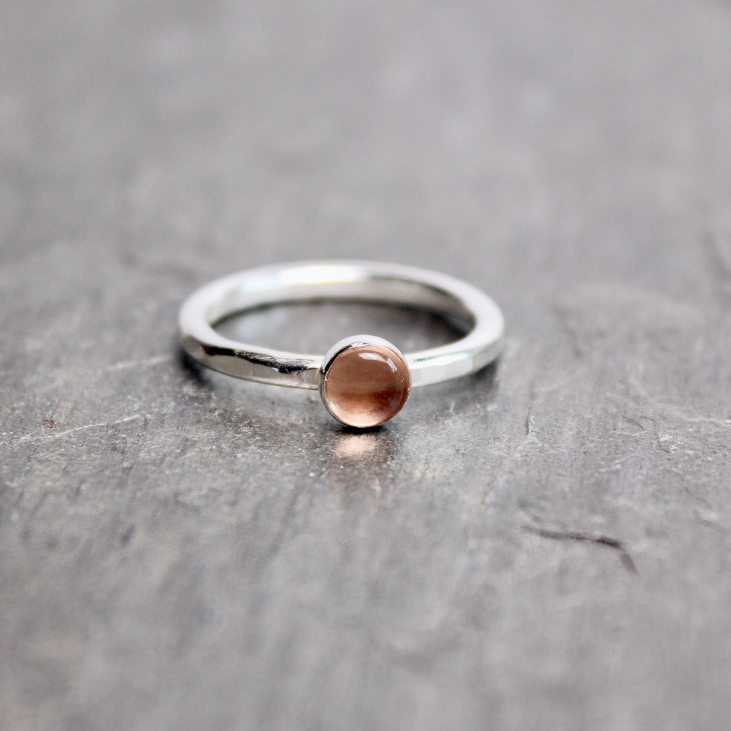 Silver ring with a round oregon sunstone on a gray surface