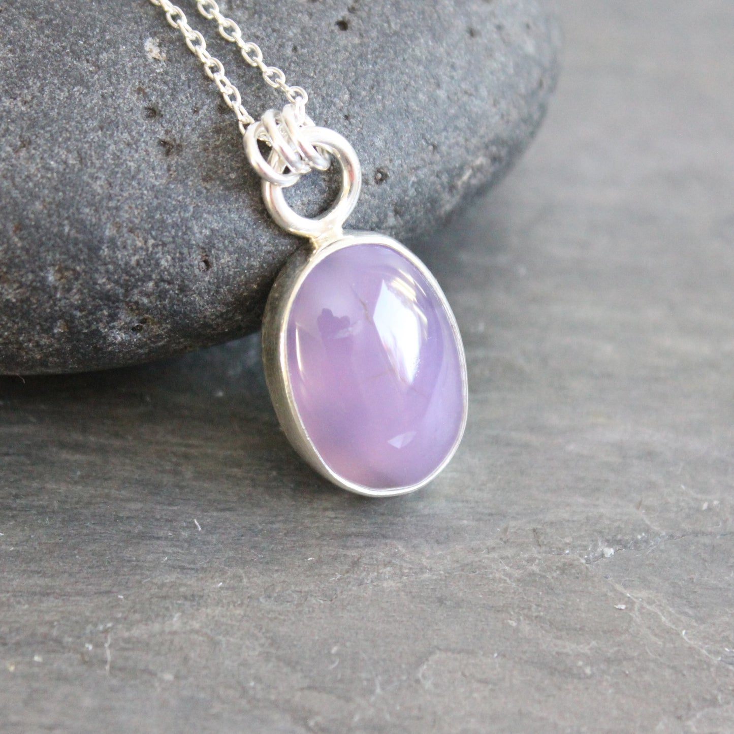 Necklace with a purple holley blue agate pendant on a gray stone surface