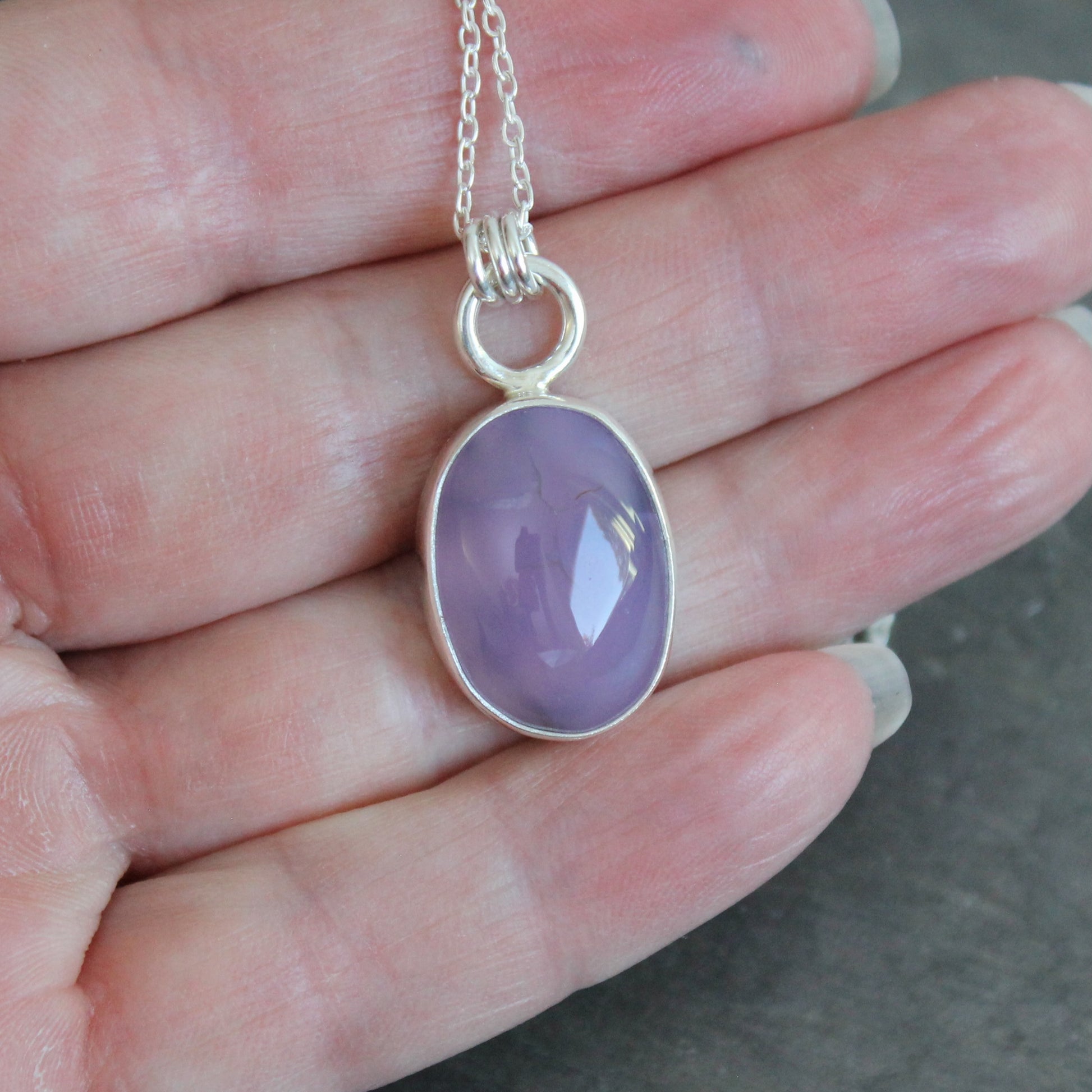 Necklace with a purple holley blue agate pendant on a hand