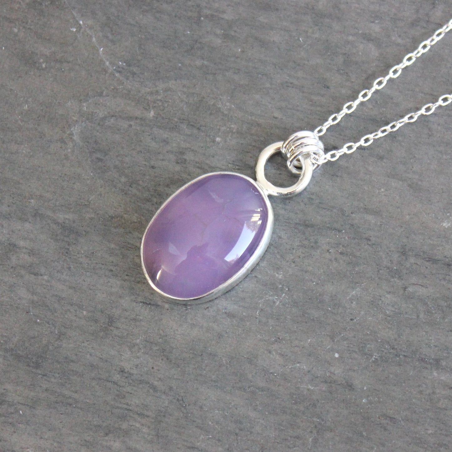 Necklace with a purple holley blue agate pendant on a gray stone surface