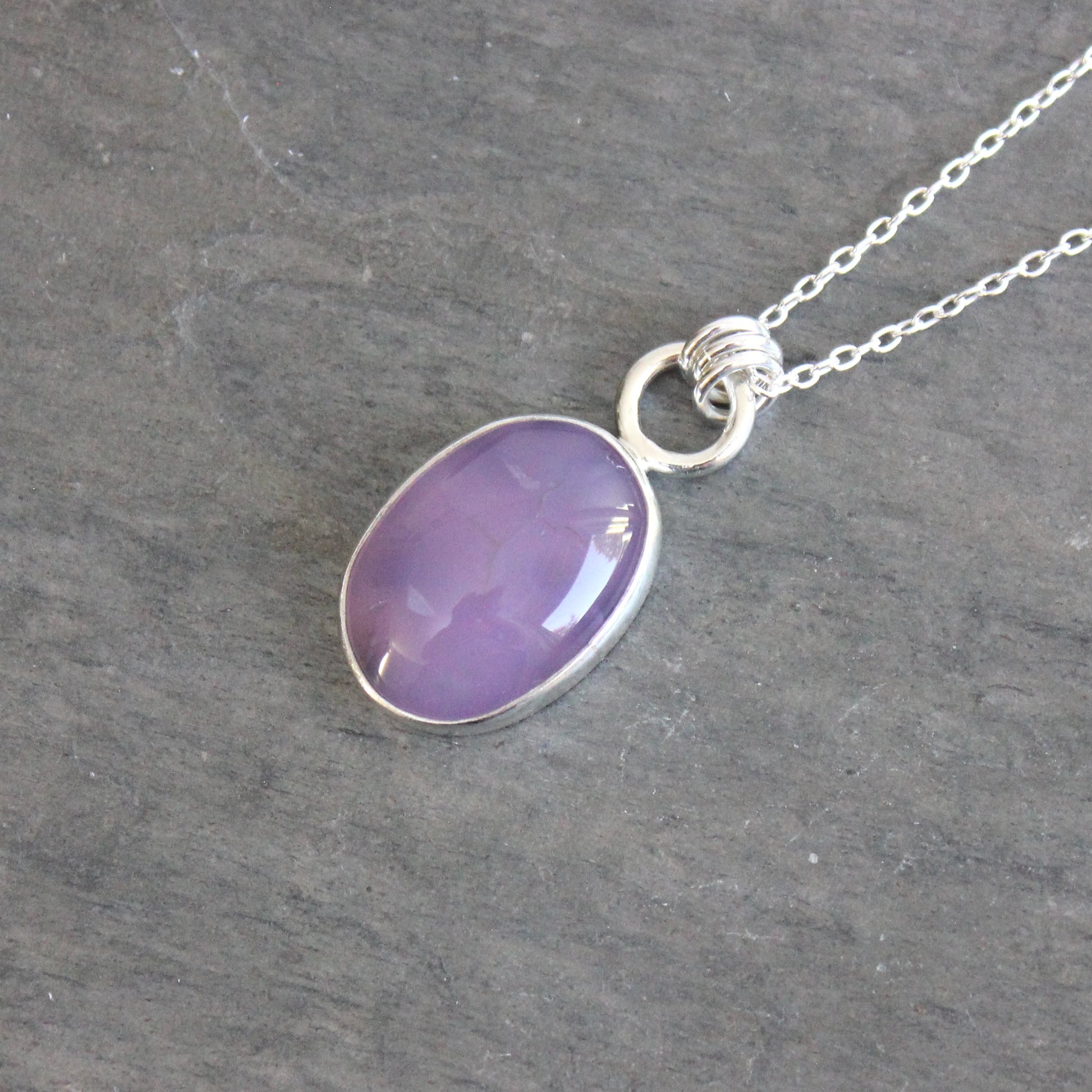 Necklace with a purple holley blue agate pendant on a gray stone surface