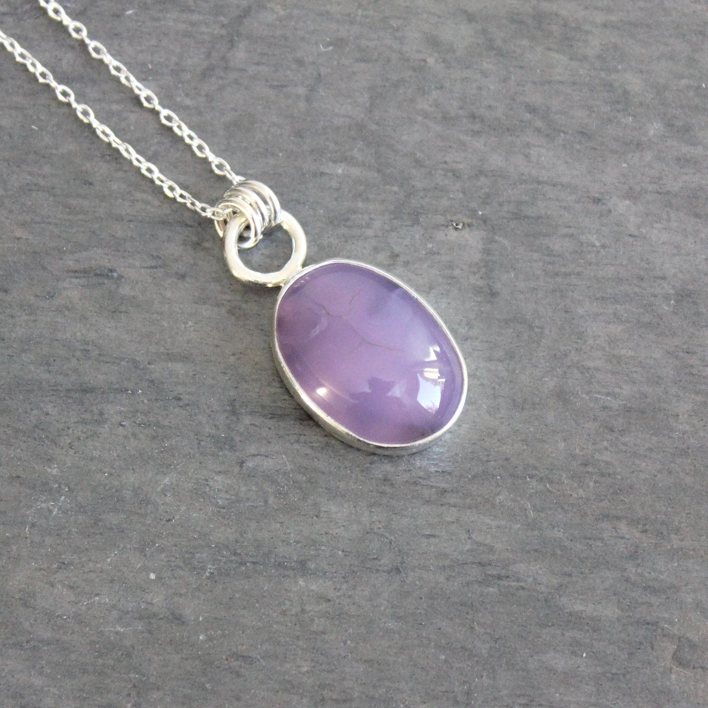 Necklace with a purple holley blue agate pendant on a gray stone surface