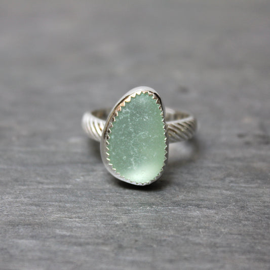 Ring with a green sea glass and silver band on a gray background