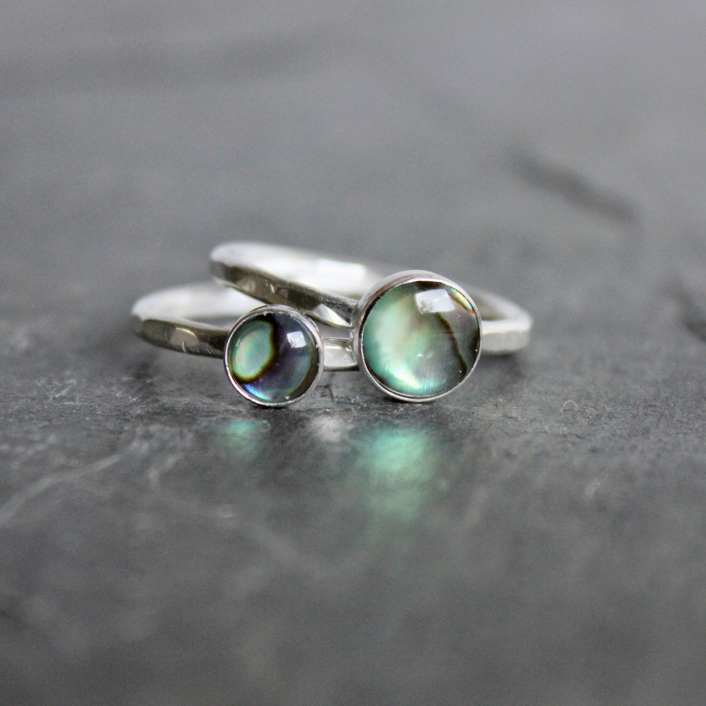 Silver ring with a green abalone cabochon on a gray surface