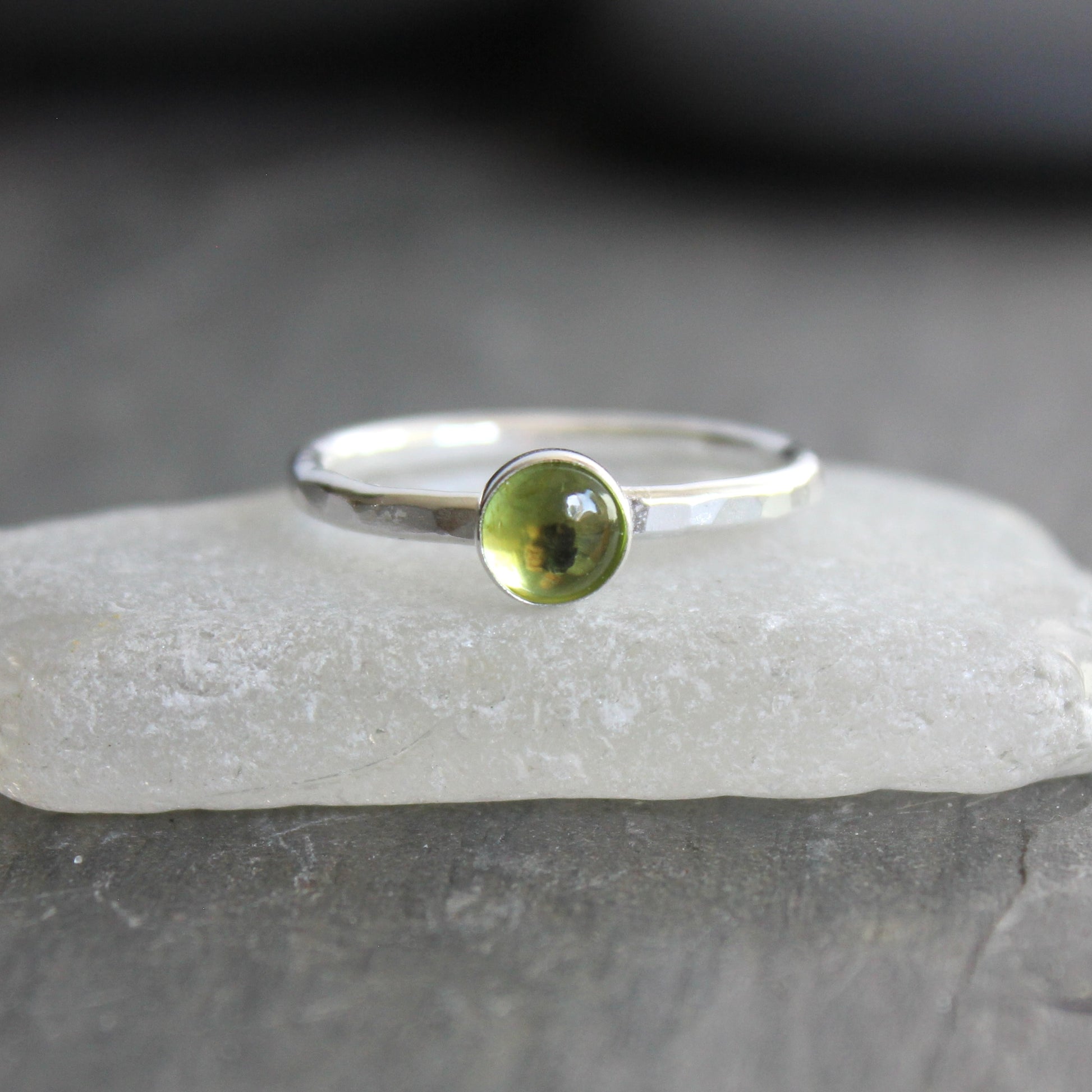 a sterling silver ring with a small green peridot gemstone