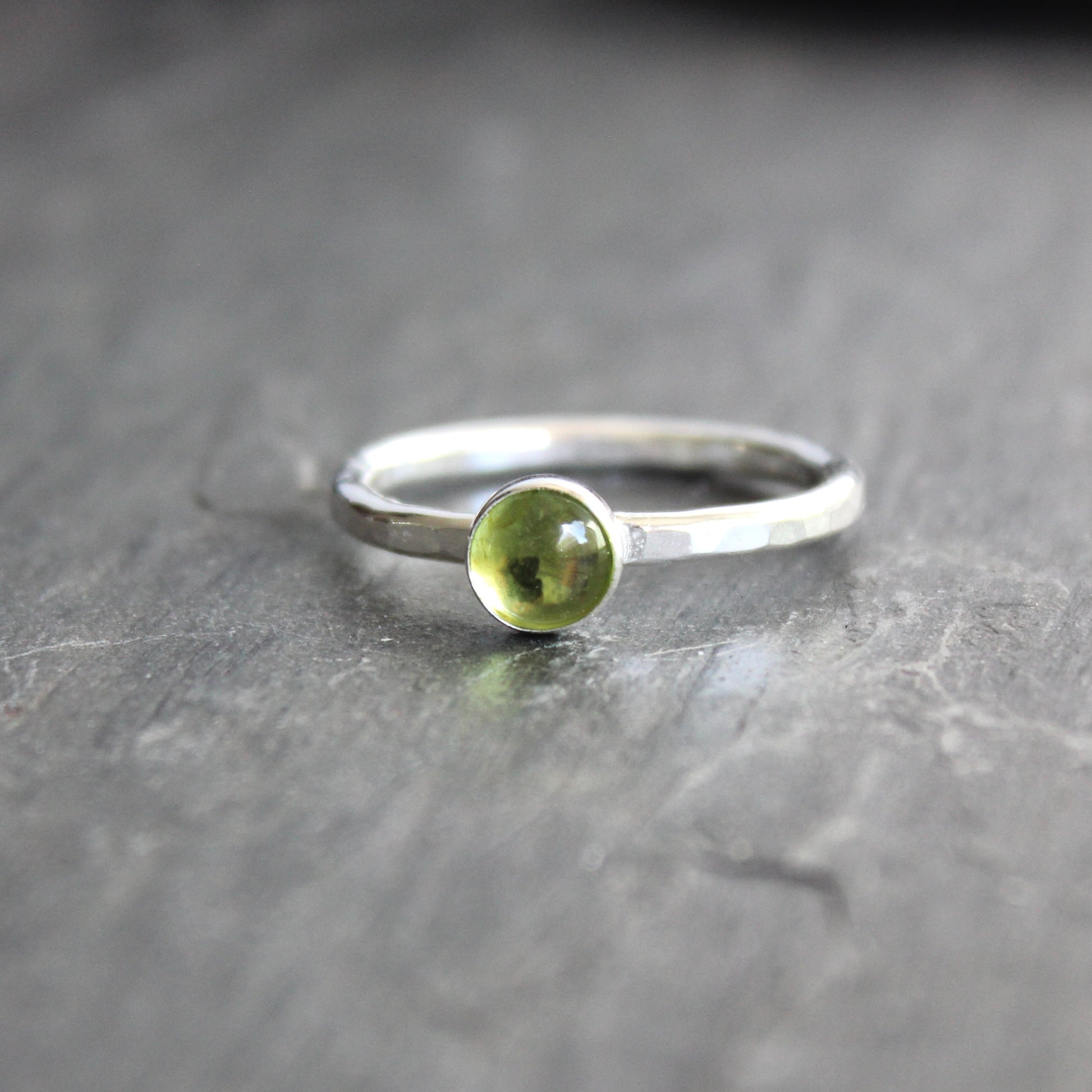 a sterling silver ring with a small green peridot gemstone