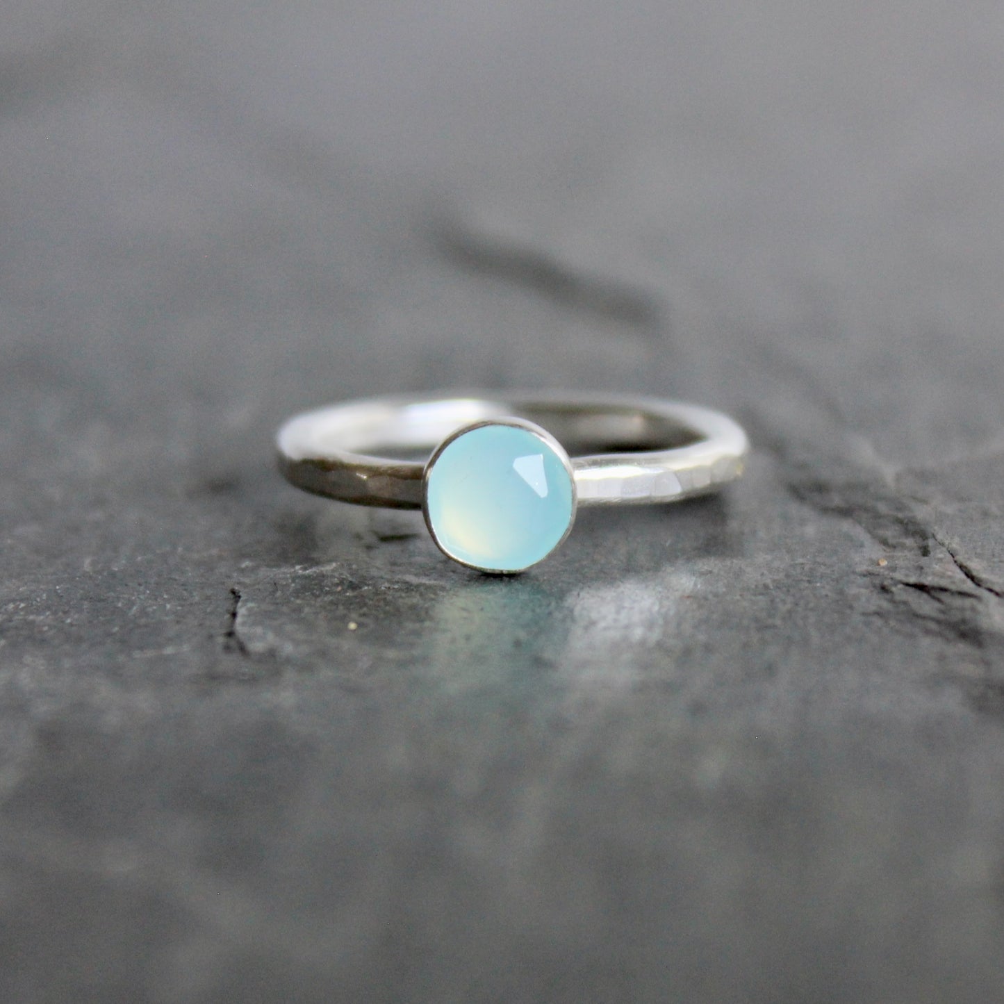 Silver ring with a light blue Peruvian chalcedony gemstone on a dark stone surface