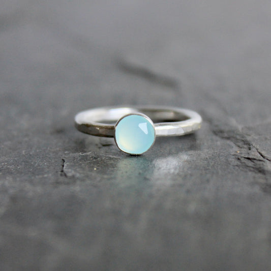 Silver ring with a light blue Peruvian chalcedony gemstone on a dark stone surface