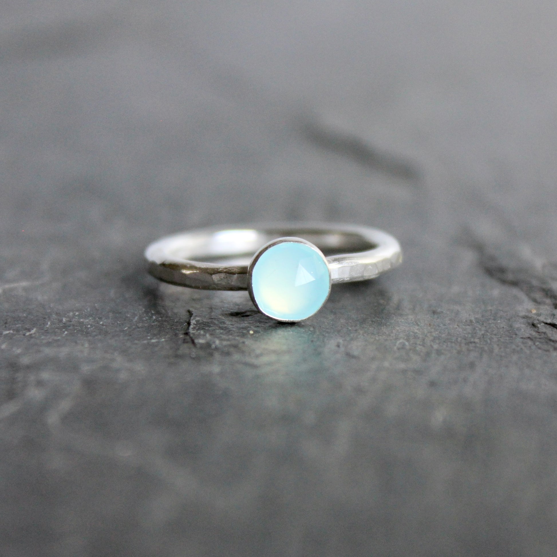 Silver ring with a light blue Peruvian chalcedony gemstone on a dark stone surface