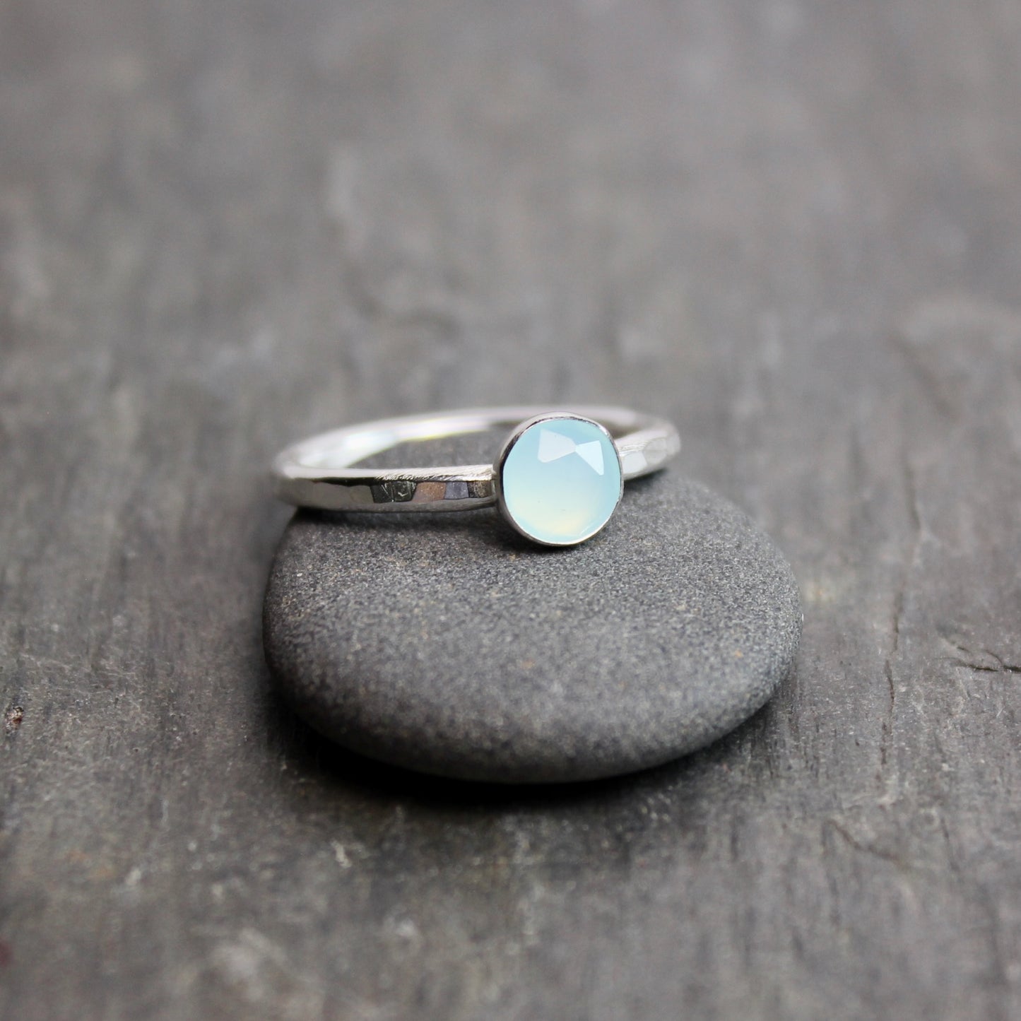 Silver ring with a light blue Peruvian chalcedony gemstone on a dark stone surface