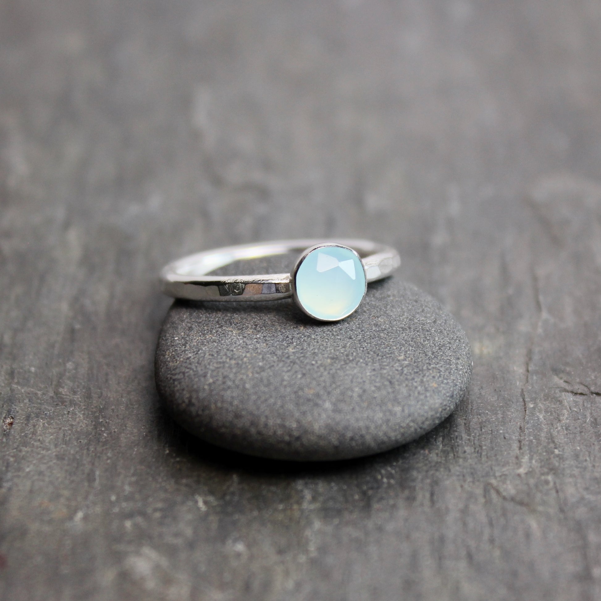 Silver ring with a light blue Peruvian chalcedony gemstone on a dark stone surface