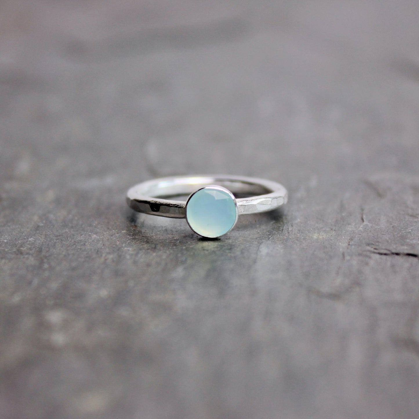 Silver ring with a light blue Peruvian chalcedony gemstone on a dark stone surface