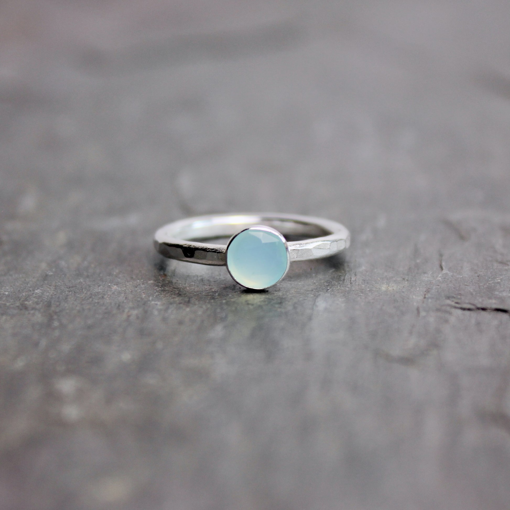 Silver ring with a light blue Peruvian chalcedony gemstone on a dark stone surface