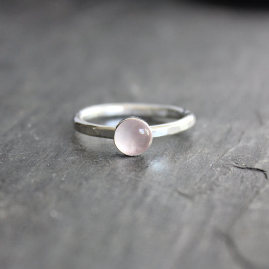 Silver ring with a pink gemstone on a dark gray surface