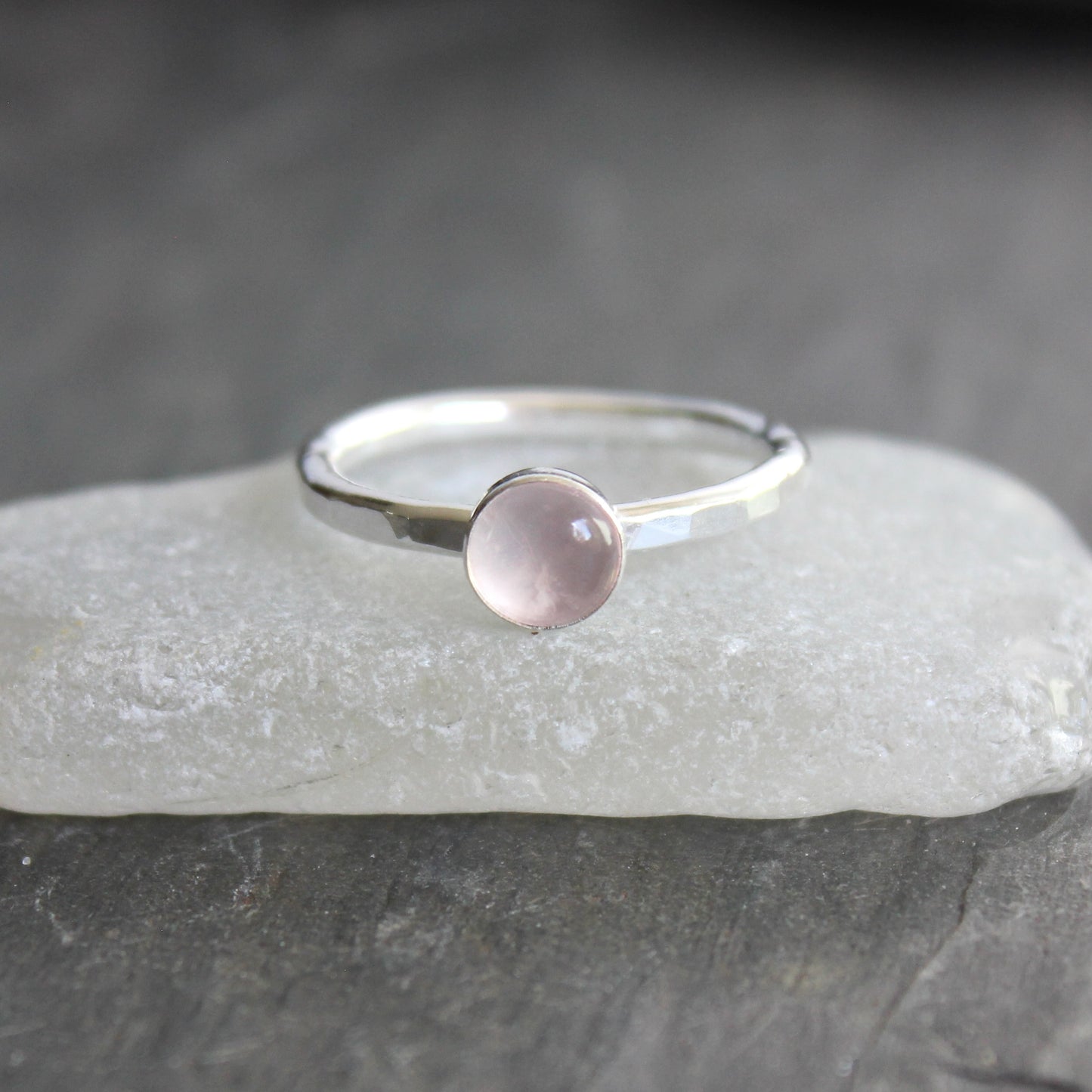 Silver ring with a pink gemstone on a gray stone surface