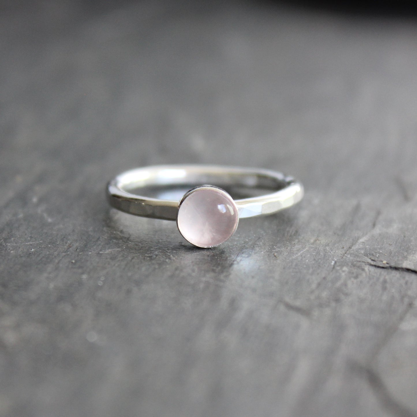 Silver ring with a pink gemstone on a dark wooden surface