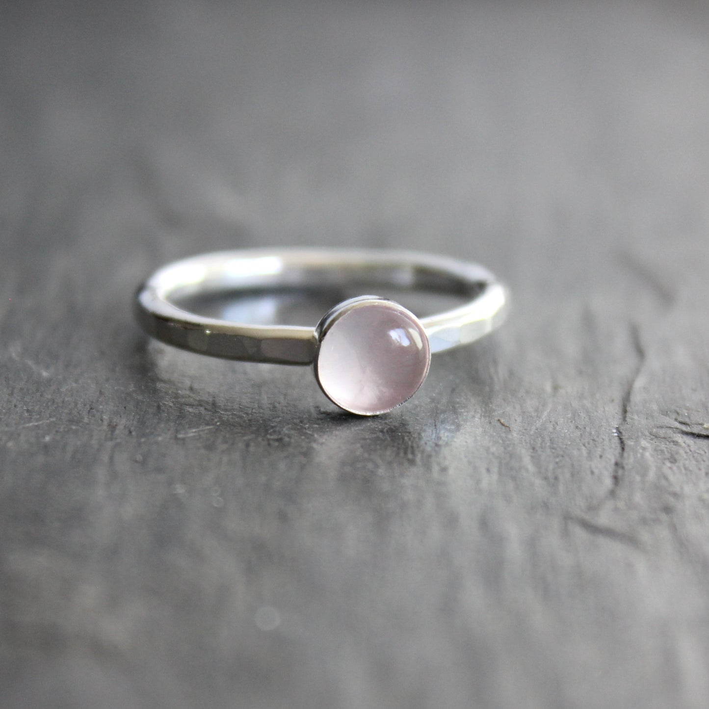 Silver ring with a pink gemstone on a gray surface