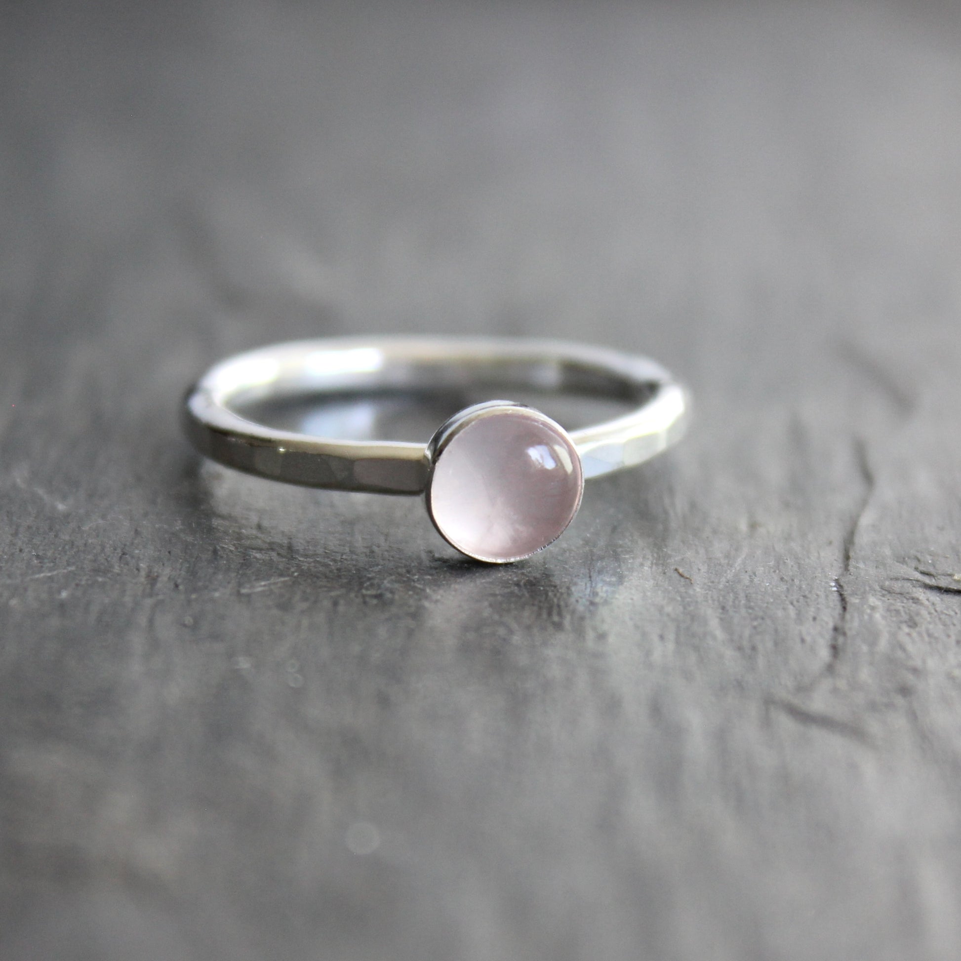 Silver ring with a pink gemstone on a gray surface